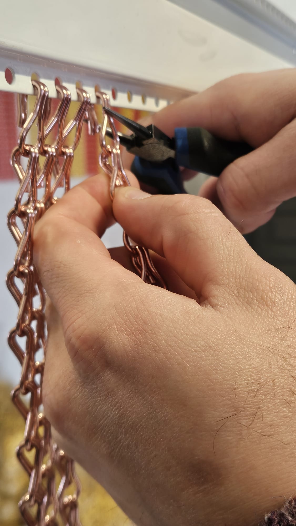 Travail manuel sur un rideau chaînette aluminium dans l’atelier Maillon Création